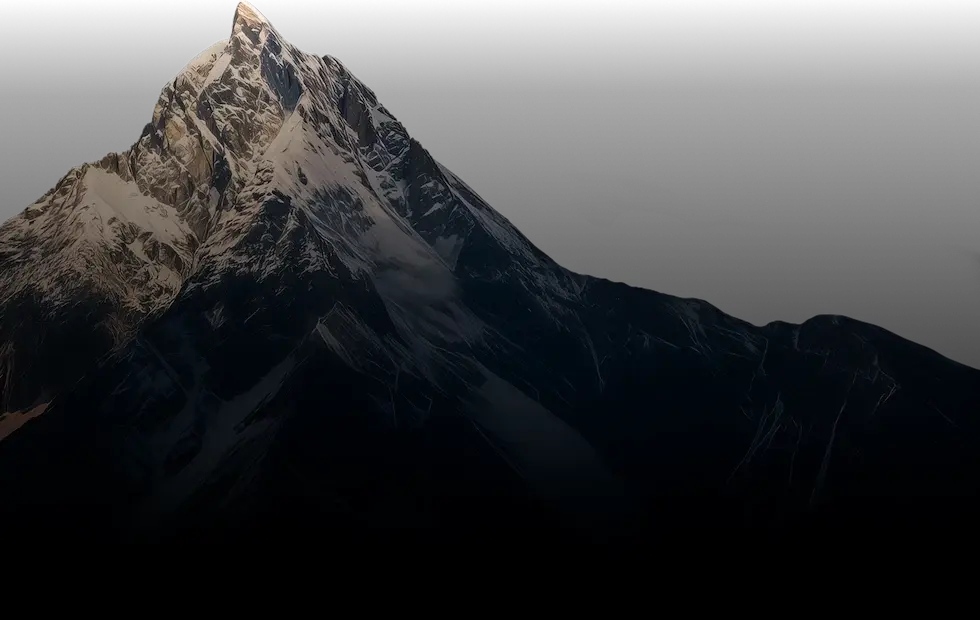 Snow-covered mountain peak illuminated against a dark background, showcasing its rugged, serene beauty.