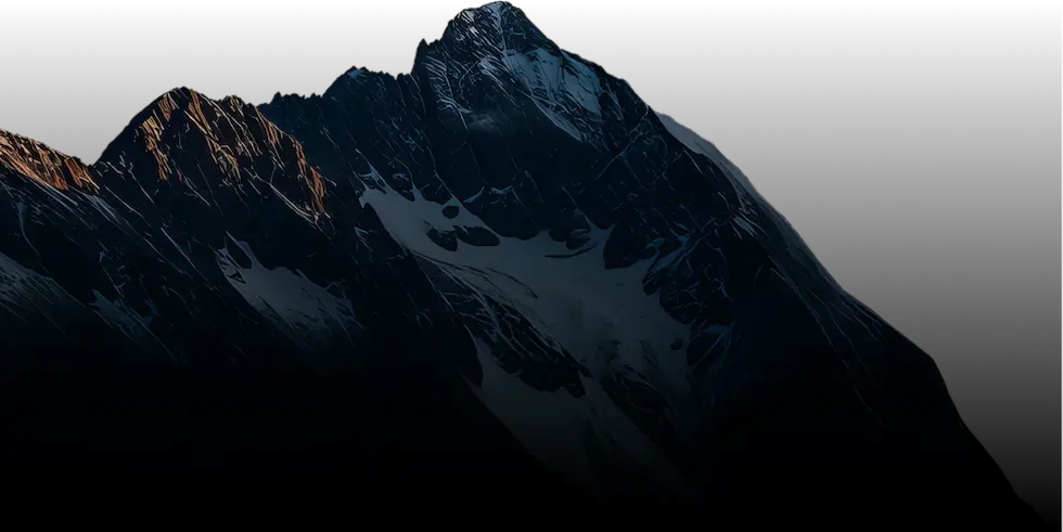 Dramatic snowy mountain peak at dusk with dark shadows and highlights from sunset.